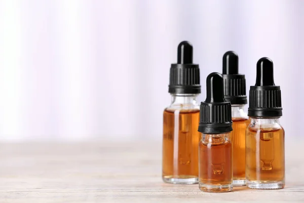 Flessen etherische oliën op tafel tegen lichte achtergrond, ruimte voor tekst. Cosmetische producten — Stockfoto