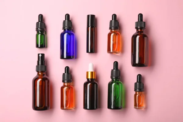 Пляшки ефірних масел на кольоровому фоні, плоский шар. Косметичні продукти — стокове фото