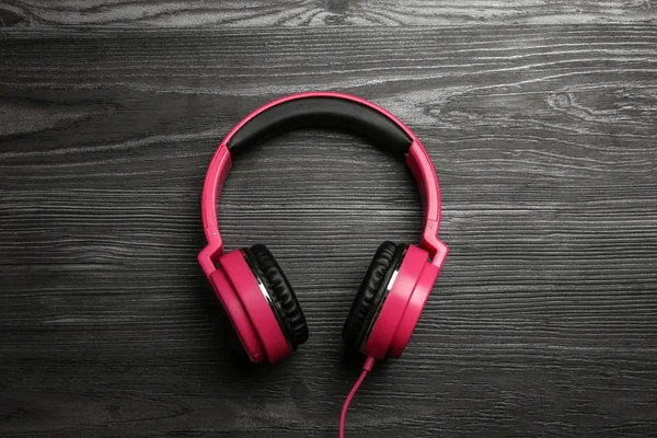 Auriculares elegantes sobre fondo de madera, vista superior — Foto de Stock