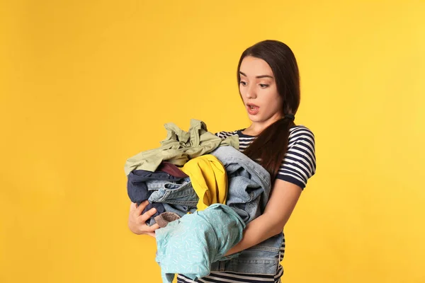 Duygusal genç kadın renkli arka plan üzerinde kirli çamaşır yığını tutan — Stok fotoğraf