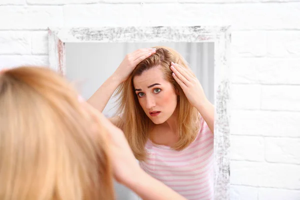Aynanın içinde saç dökülmesi sorunu olan genç bir kadın. — Stok fotoğraf