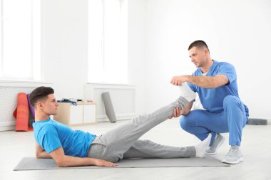 Rehabilitasyon merkezinde erkek hasta ile çalışan profesyonel fizyoterapist