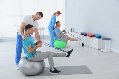 Professional physiotherapists working with patients in rehabilitation center clipart