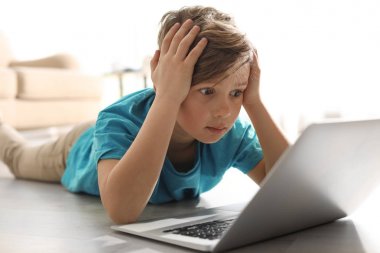 Kapalı mekanda dizüstü bilgisayar la şok küçük çocuk. İnternet tehlikesi