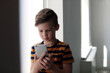 Kapalı akıllı telefon ile üzgün küçük çocuk. İnternet tehlikesi