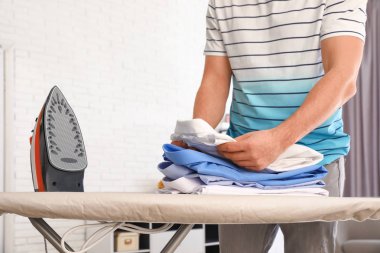 Evde ütü tahtasıüzerinde giysi katlayan adam, closeup