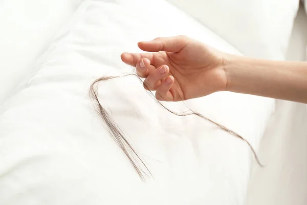 Mujer recogiendo el pelo largo caído de la almohada, primer plano — Foto de Stock