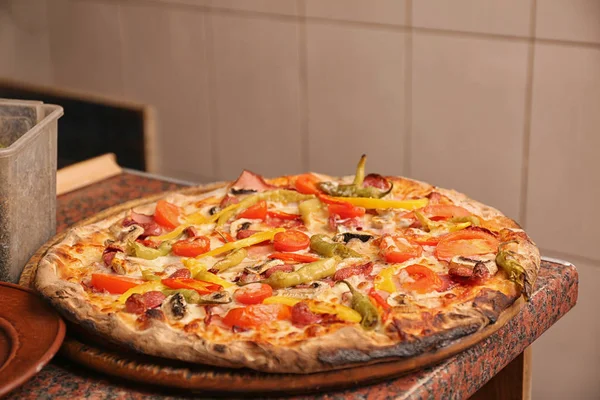 Träskiva med läcker pizza på bord i restaurang. Färsk från ugnen — Stockfoto