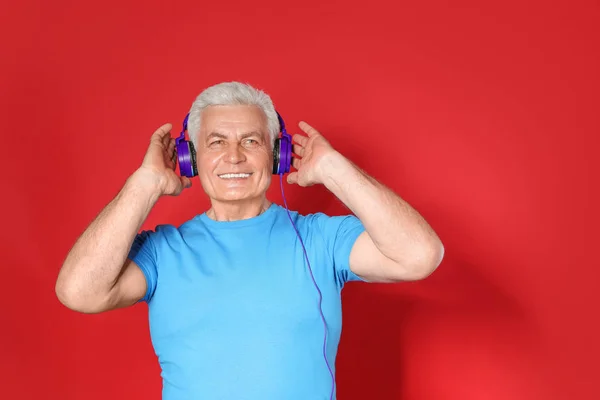 Mature man enjoying music in headphones on color background. Space for text — Stock Photo, Image