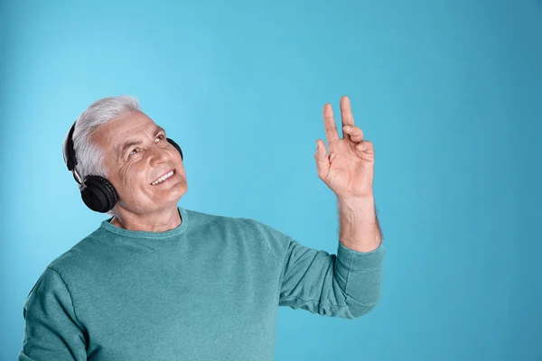 Mature man enjoying music in headphones on color background. Space for text — Stock Photo, Image