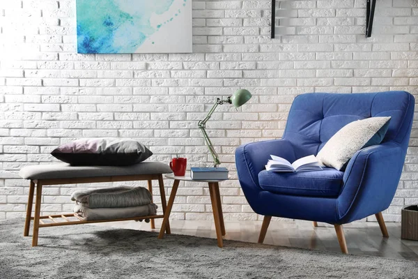 Kamer interieur met comfortabele meubels en boeken in de buurt van Brick Wall — Stockfoto