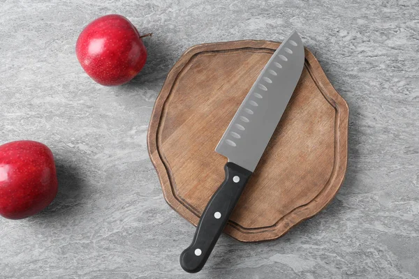 Planche à découper avec couteau de chef et pommes sur fond gris, plat — Photo