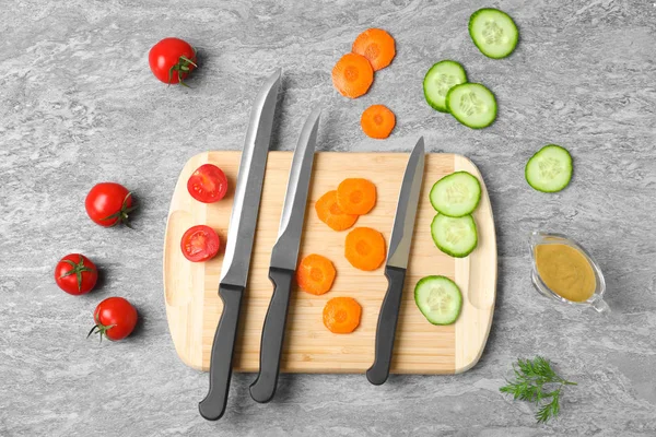 Platte lay compositie met snijplank, messen en groenten op grijze achtergrond — Stockfoto