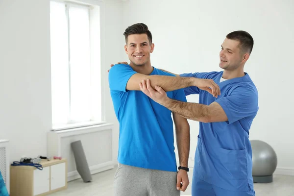 Professional physiotherapist working with male patient in rehabilitation center — Stock Photo, Image