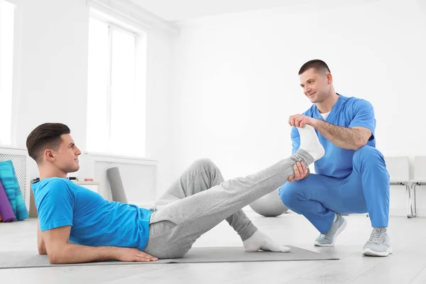 Professionelle Physiotherapeutin arbeitet mit männlichen Patienten im Rehabilitationszentrum — Stockfoto