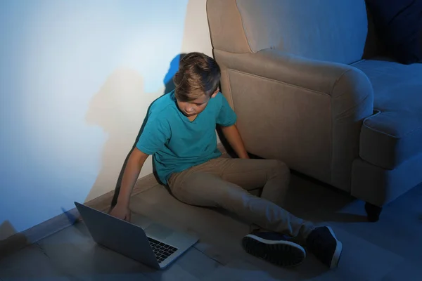 Litet barn med bärbar dator på golvet i mörkt rum. Risk för Internet — Stockfoto