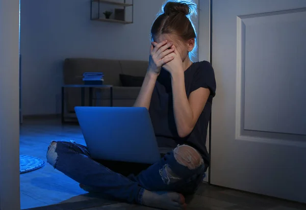Menina adolescente assustada com laptop no chão no quarto escuro. Perigo da internet — Fotografia de Stock