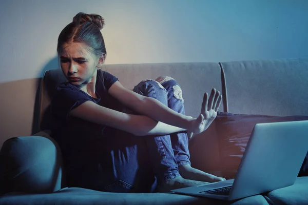 Menina adolescente assustada com laptop no sofá no quarto escuro. Perigo da internet — Fotografia de Stock