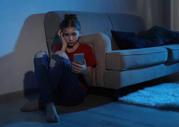 Menina adolescente emocional com smartphone no quarto escuro. Perigo da internet — Fotografia de Stock