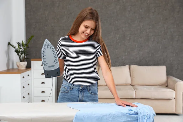 Молодая женщина гладит одежду на борту дома — стоковое фото
