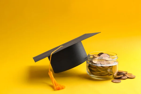 Tarro de vidrio, monedas y sombrero de graduación sobre fondo de color. Espacio para texto —  Fotos de Stock