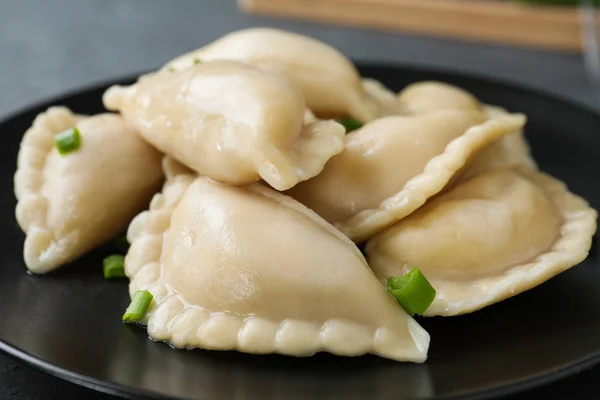 Smakelijke dumplings geserveerd met groene ui op plaat, close-up — Stockfoto