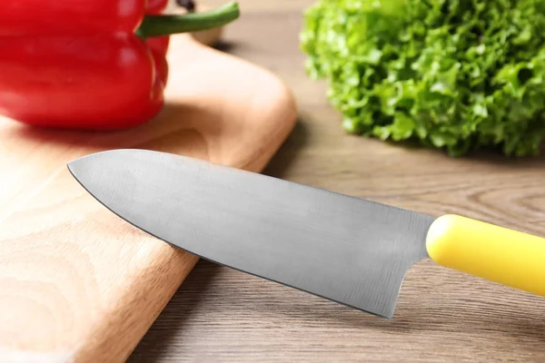 Tabla de cortar y cuchillo de chef afilado en mesa de madera — Foto de Stock