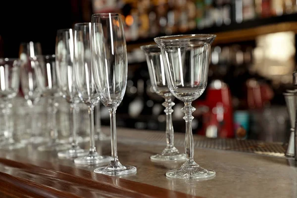 Différents verres propres vides sur le comptoir dans le bar — Photo