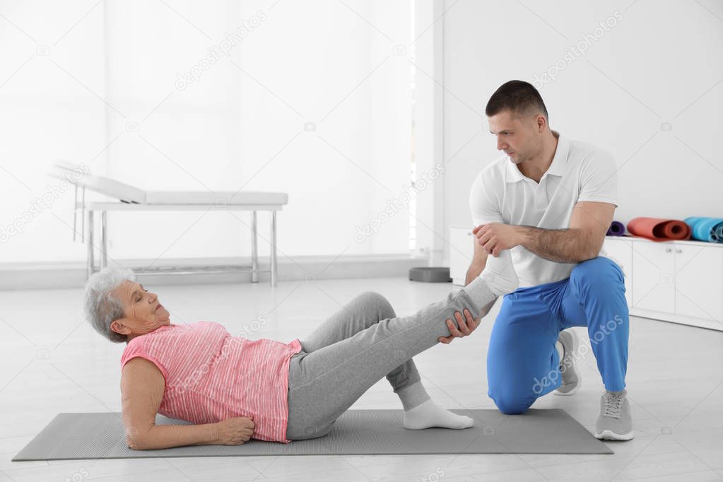 Professional physiotherapist working with elderly patient in rehabilitation center. Space for text
