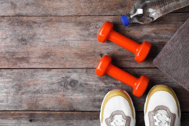 Ahşap arka planda metin için dumbbells, spor ayakkabıları ve alan ile düz yatıyordu kompozisyon