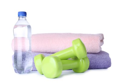 Şık halterler, bir şişe su ve beyaz arka plan havlular. Ev fitness