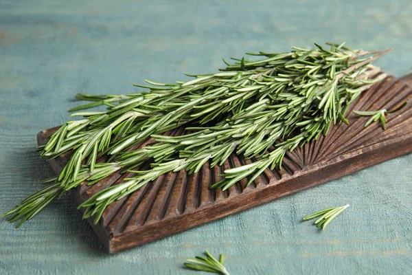 Holzbrett mit frischen Rosmarinzweigen auf dem Tisch — Stockfoto