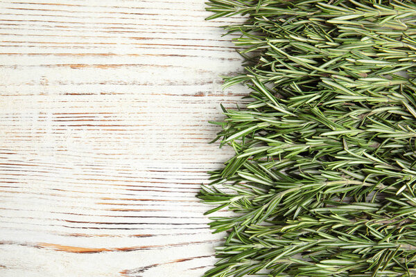 Fresh rosemary twigs on wooden table, top view. Space for text