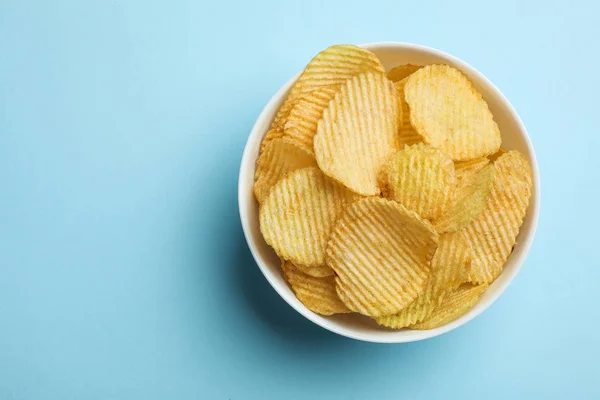 Heerlijke knapperige aardappelchips in kom op kleur achtergrond, bovenaanzicht met ruimte voor tekst — Stockfoto