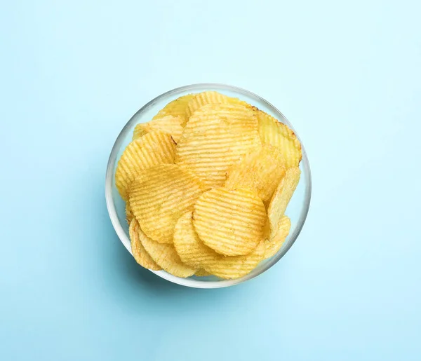 Heerlijke knapperige aardappelchips in Bowl op kleur achtergrond, bovenaanzicht — Stockfoto