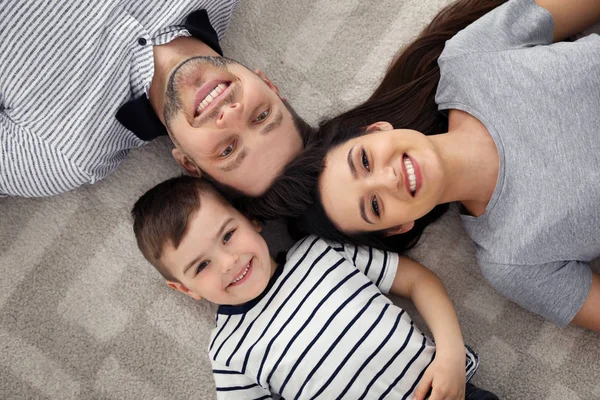 Gelukkige ouders en hun zoon liggen samen op de vloer, uitzicht van bovenaf. Family time — Stockfoto