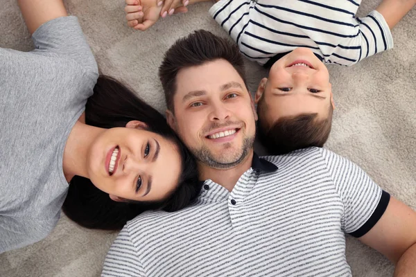 Pais felizes e seu filho deitados juntos no chão, vista de cima. Tempo de família — Fotografia de Stock