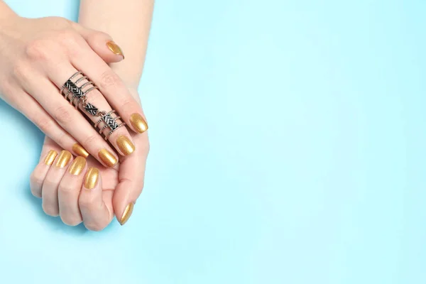 Frau zeigt gepflegte Hände mit goldenem Nagellack auf farbigem Hintergrund, Draufsicht. Raum für Text — Stockfoto