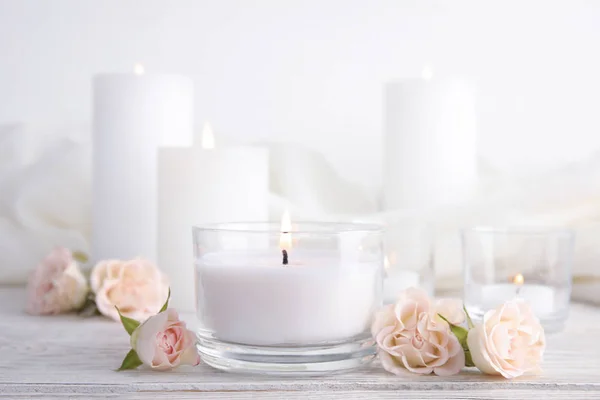 Composición con vela aromática ardiente y rosas sobre mesa de madera — Foto de Stock