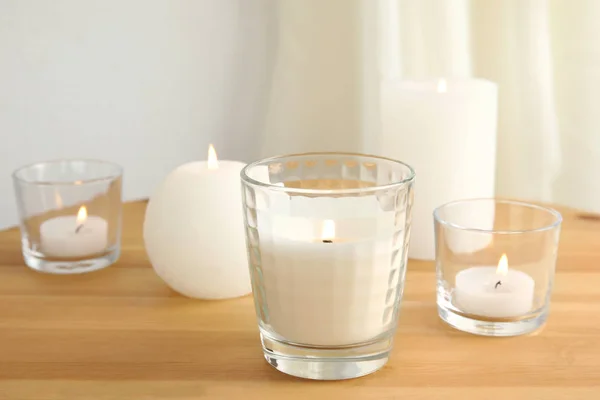 Velas aromáticas ardientes diferentes en mesa de madera — Foto de Stock