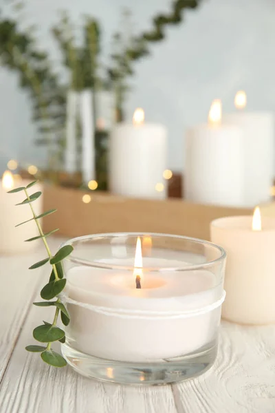 Burning aromatic candle and eucalyptus branch on table. Space for text — Stock Photo, Image