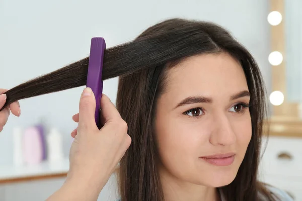 Friseur verwendet modernes Flachbügeleisen, um die Frisur des Kunden im Salon zu stylen — Stockfoto