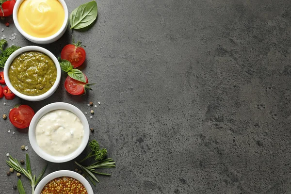 Cuencos con diferentes salsas e ingredientes sobre fondo gris, la puesta plana. Espacio para texto — Foto de Stock