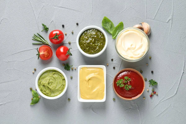 Плоская композиция с различными соусами и ингредиентами на сером фоне — стоковое фото