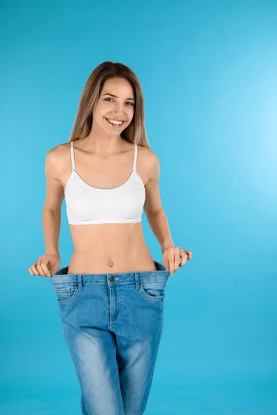 Schlanke Frau in übergroßen Jeans auf farbigem Hintergrund. perfekter Körper — Stockfoto