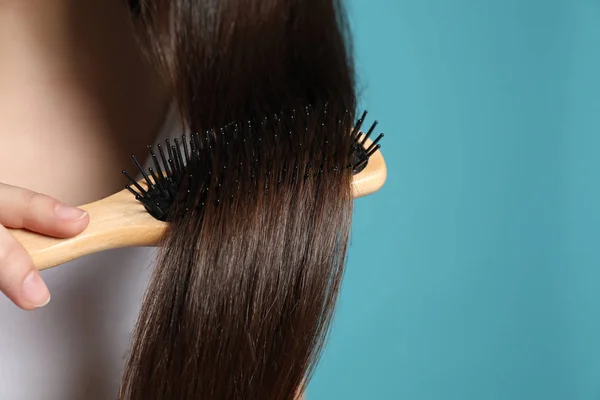 Mujer con cepillo de pelo sobre fondo de color, primer plano. Espacio para texto — Foto de Stock