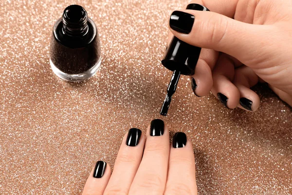 Vrouw toepassen van zwarte nagellak op glanzende kleur achtergrond, close-up — Stockfoto