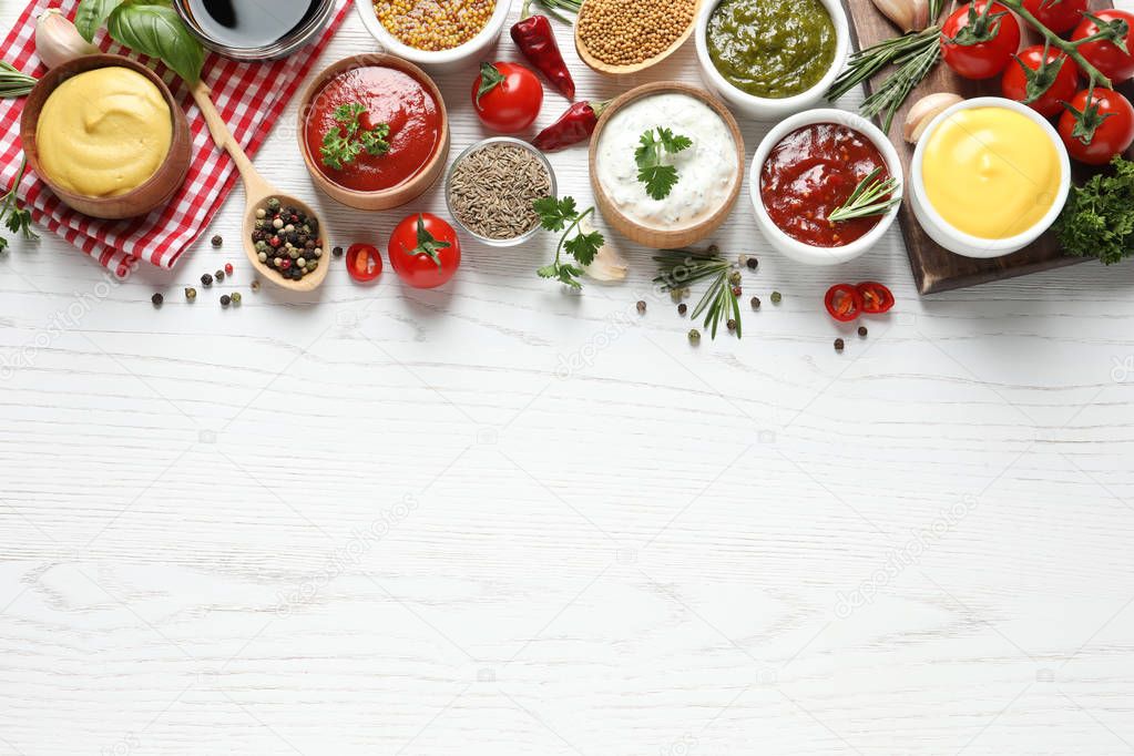 Flat lay composition with different sauces and space for text on white wooden background