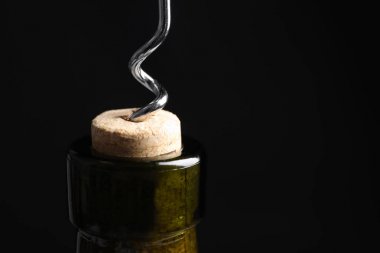 Siyah arka planda tirbuşonlu şarap şişesi açmak, yakın çekim. Metin için alan