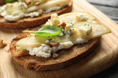 Lezzetli armut bruschetta ile ahşap tahta masa, yakın plan.